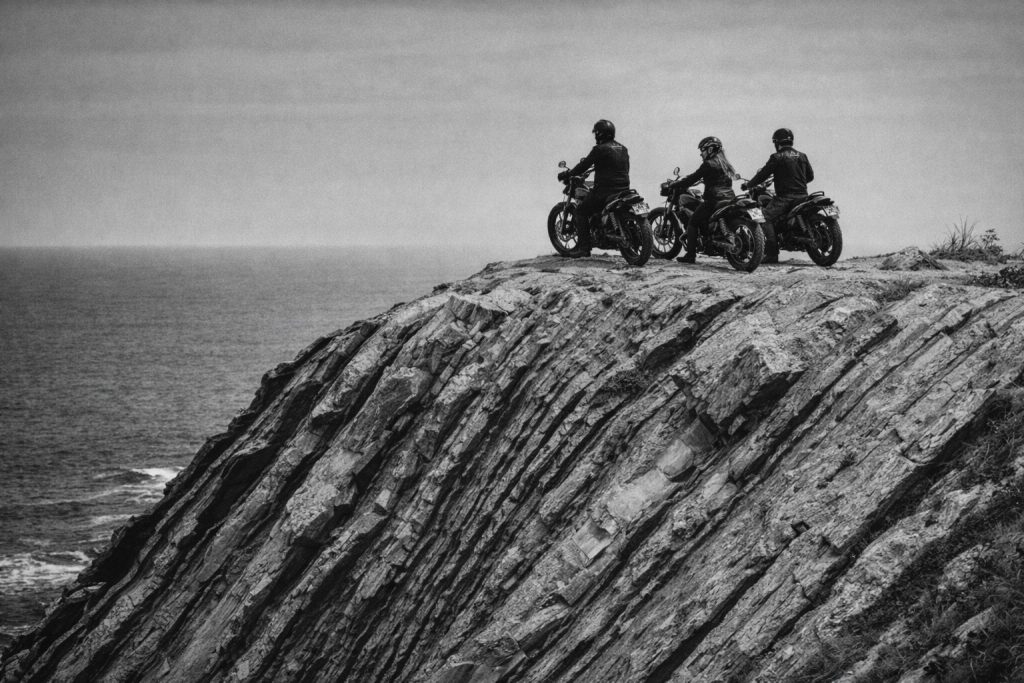 motorcyclists on rugged cliff edge overlooking ocean coastal road basque coast scenic landscape