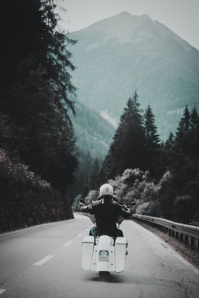 person-riding-white-motorcycle-along-paved-road