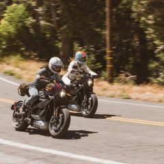 Two riders traveling side by side on LiveWire electric motorcycles on an open road.