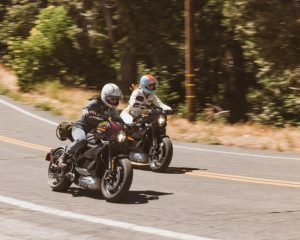 Two riders traveling side by side on LiveWire electric motorcycles on an open road.