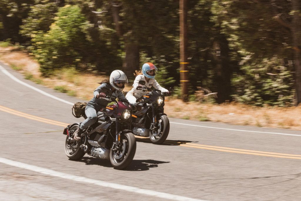 Two riders traveling side by side on LiveWire electric motorcycles on an open road.