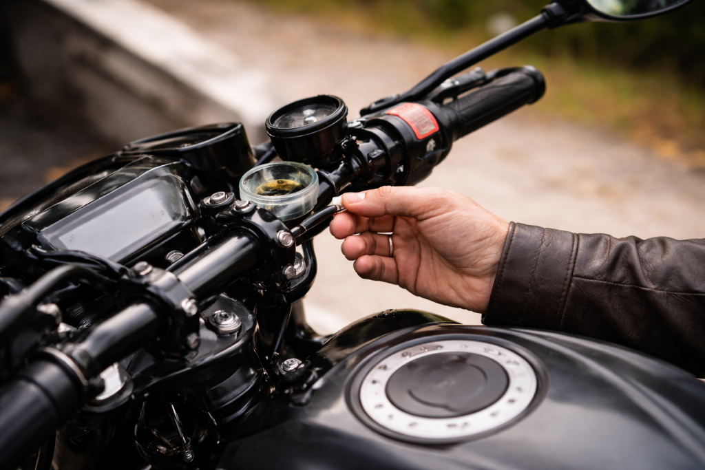 Close-up of rider inspecting the front brake fluid reservoir on a modern motorcycle handlebar in natural daylight.