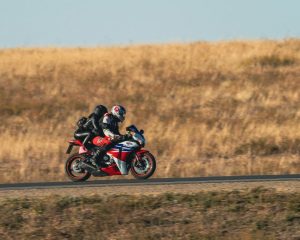 a-man-rwith-woman-passenger-riding-a-red-motorcycle-down-a-road-kJfugpeDwL0